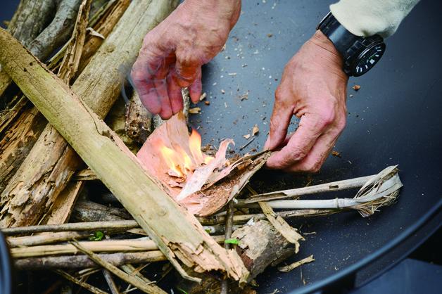 （4）火口が燃えたら、台にした樹皮ごと炎を焚き火台に運び、焚付の下に置く