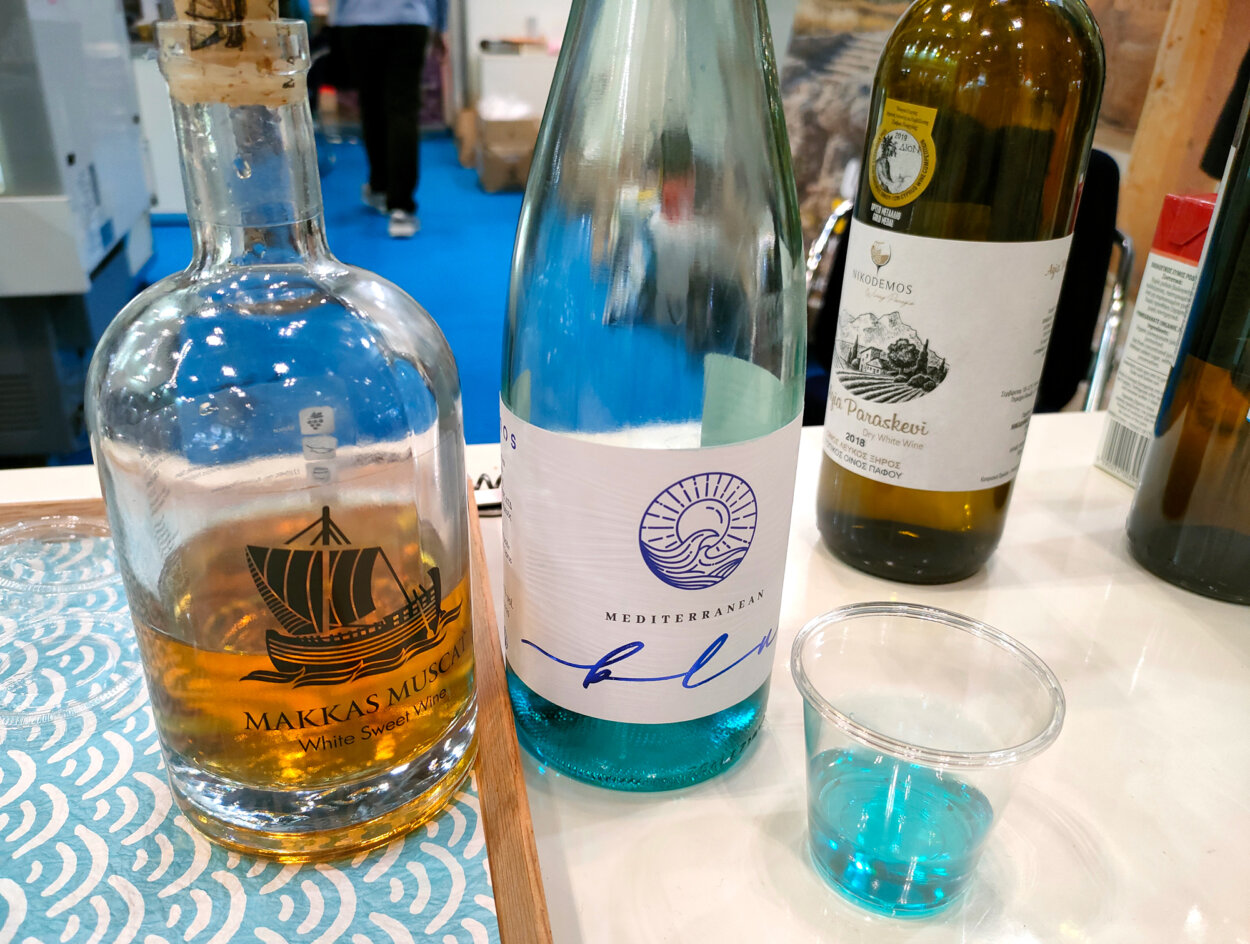 キプロスブースでは、珍しい青いワイン「メリディアンブルー」（左）の試飲も。ブランデーのように香り高いデザートワイン「マッカス・マスカット」。こちらはまだ日本未発売