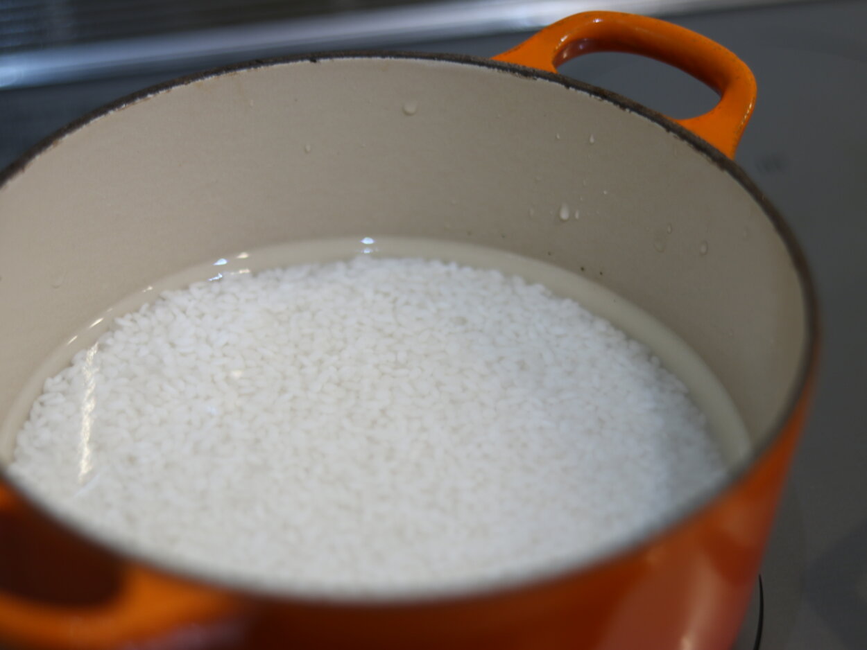 といだ白米はしばらくザルに上げておいてから、鍋にしかける。通常の炊き方より水を減らすのがおすすめ