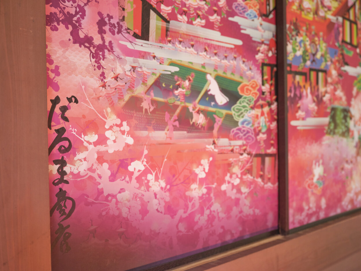 『だるま商店』は極彩色で影絵のような画風が特長。熊野古道をテーマにした曼荼羅絵や、祇園の都おどりなど、歴史や伝統を題材に、徹底的に調査・分析して往時を描き出す。