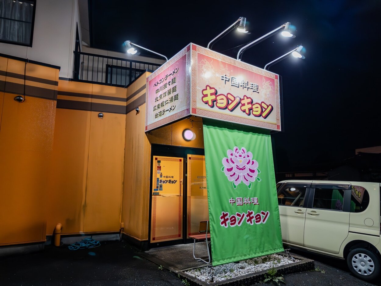 オレンジの壁とピンクの看板、緑のタペストリーの派手な店構え